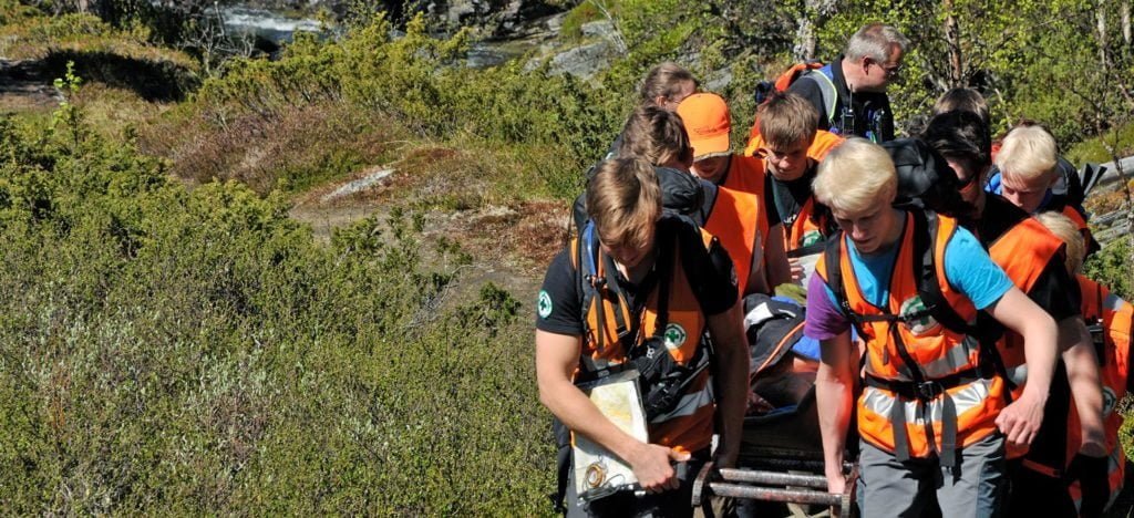 bilder av flere personer som går i skogen med oransje vester