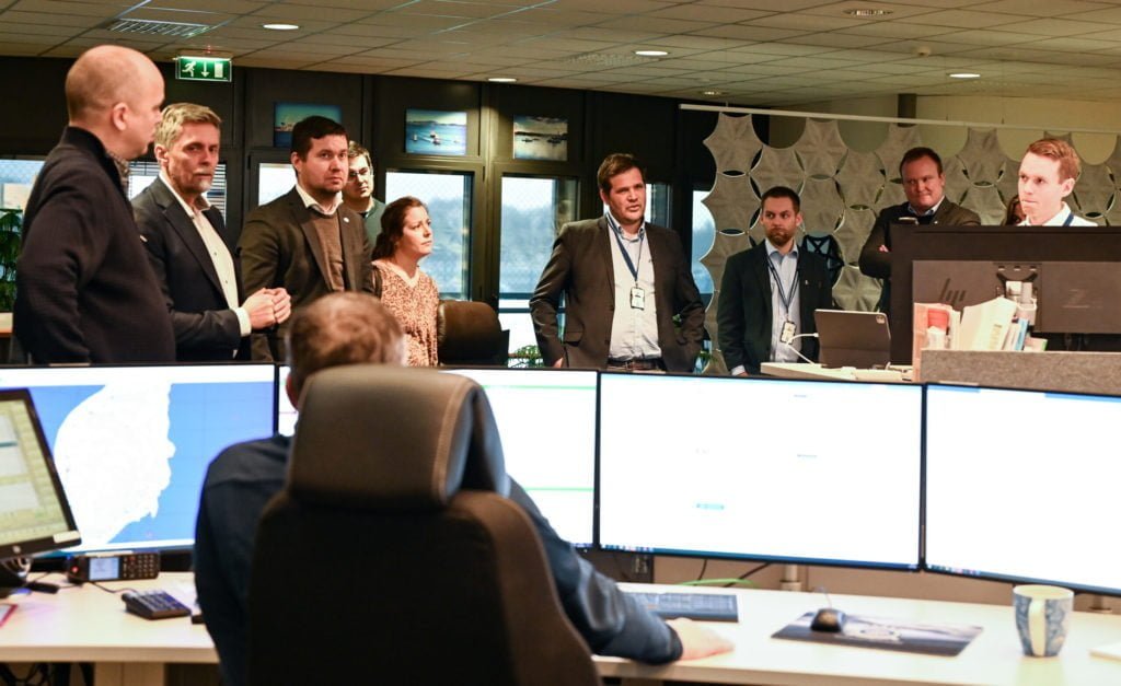 En gruppe mennesker står på rekke og er på besøk i en operasjonssentral.