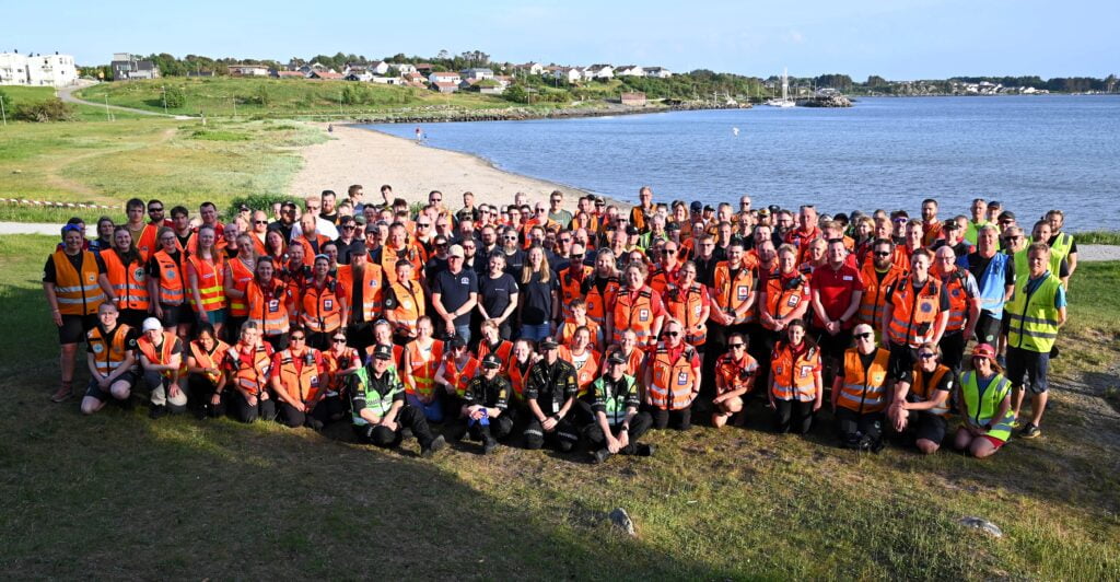 Gruppebilde av mange mennesker ved en strand