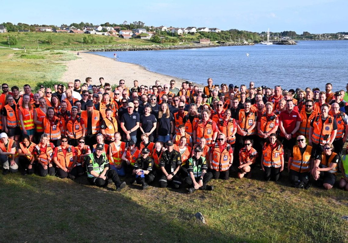 Gruppebilde av mange mennesker ved en strand