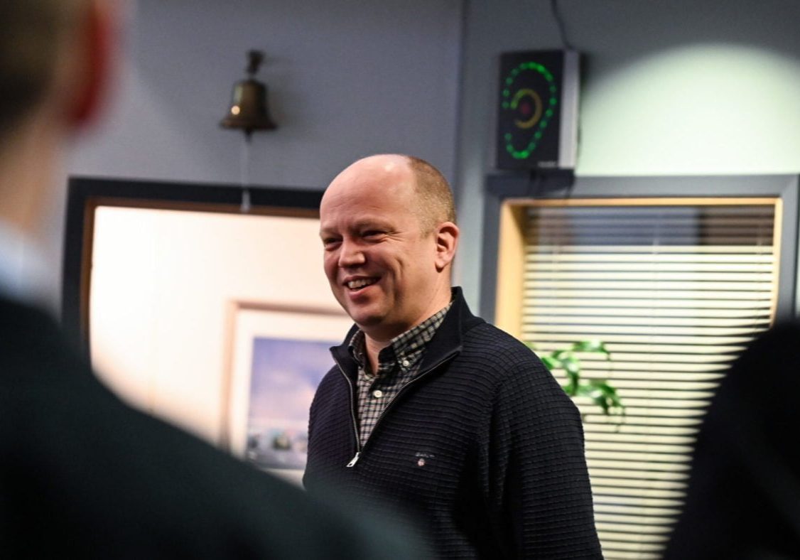 Mann med sort genser smiler.