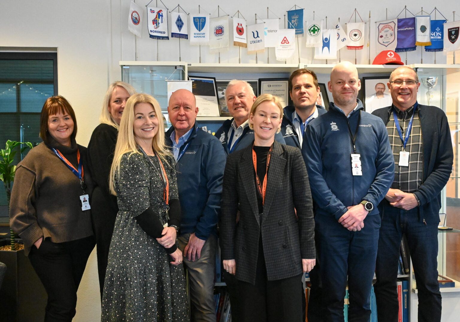 En gruppe mennesker står på rekke og ser på fotografen,