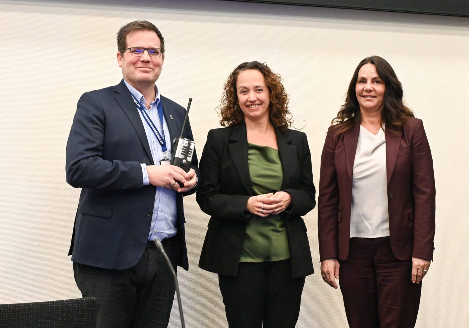 Tre personer står ved siden av hverandre og ser på kamera