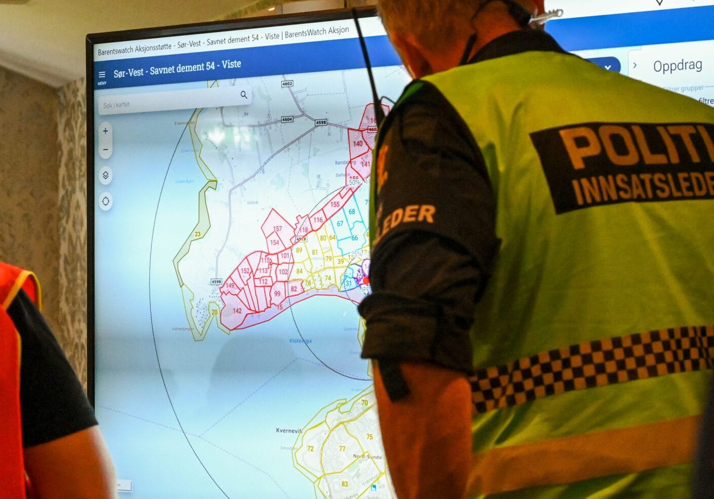 En politimann ser på en storkjerm med kart på.