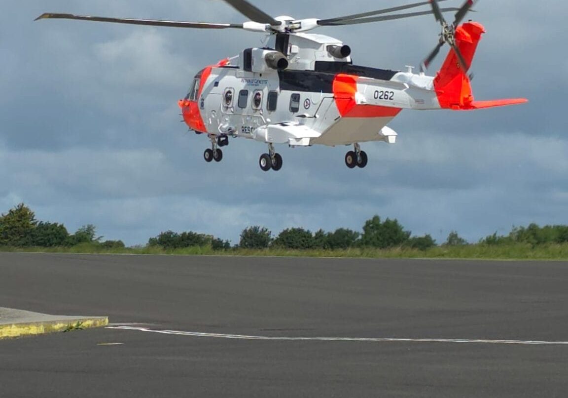 Oransjt og hvitt helikopter tar av fra bakken.