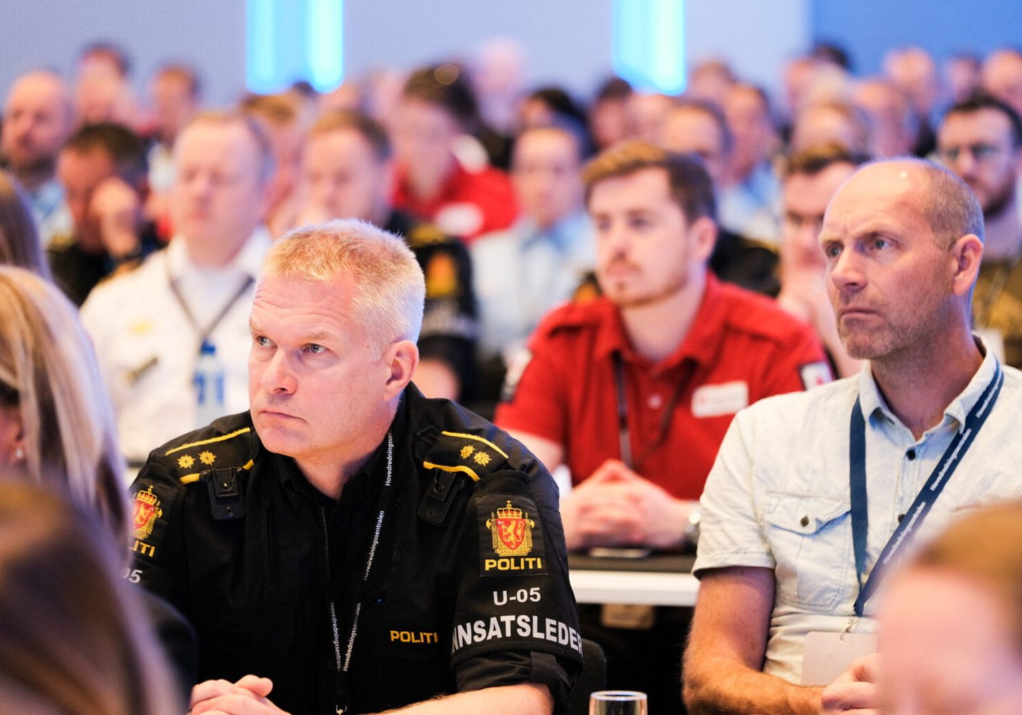 Mennesker sitter i en innendørs sal.