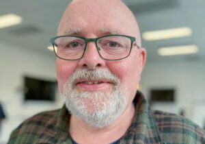 Portrett av mann med briller og skjegg.