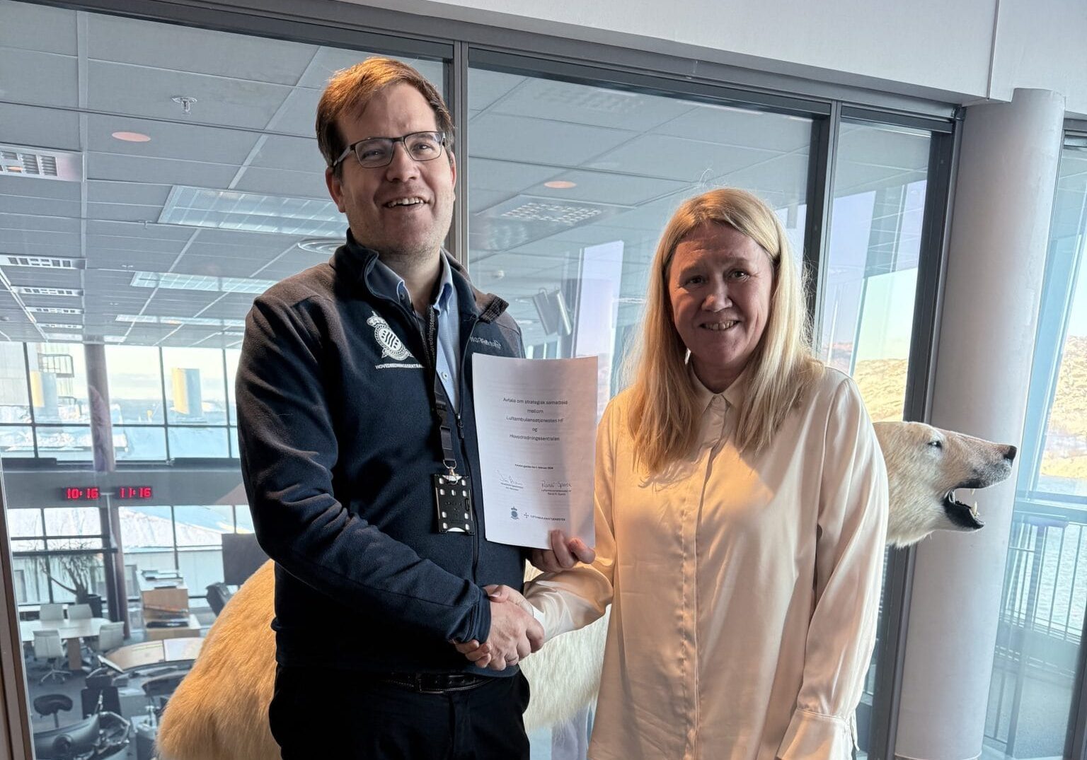 En mann og en kvinne står foran en isbjørn og holder et dokument.